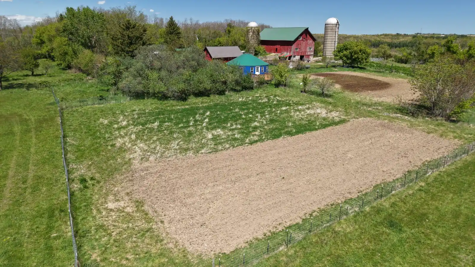 Fenced, freshly worked garden plot with the red barns and silos behind it at the Goldstein Farm, Walworth County, Wisconsin
