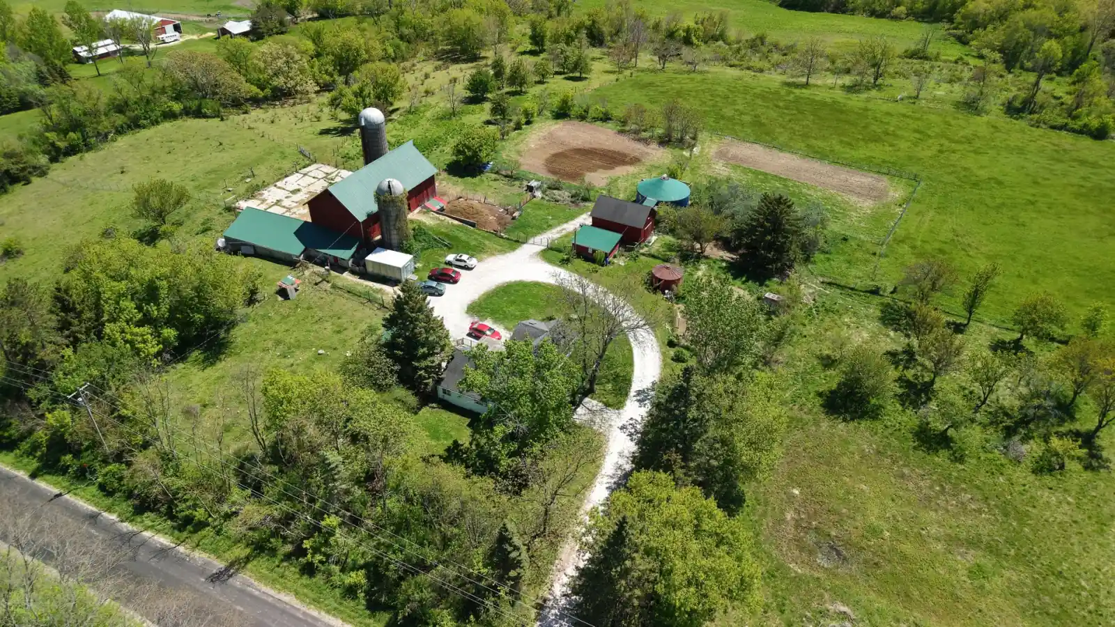 Aerial view of the Goldstein Farm farmstead in Spring Prairie, Wisconsin: red timber-frame barn, silo, farmhouse and circular gravel drive off Kniep Road