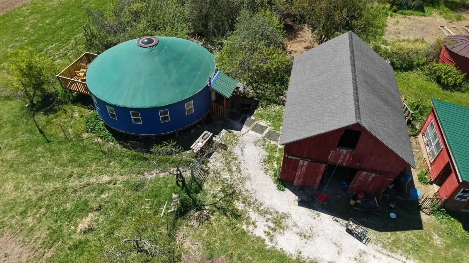 The four-season heated yurt with its green roof beside the red barn at the Goldstein Farm, Spring Prairie, Wisconsin