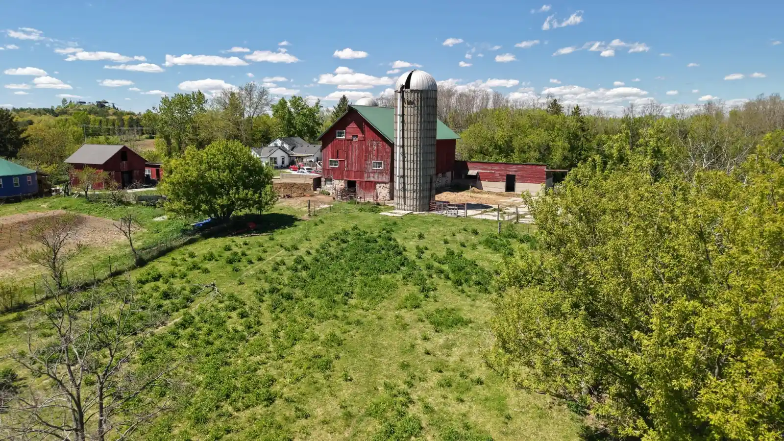 Red barn and silo above a green pasture slope at the Goldstein Farm near East Troy, Wisconsin