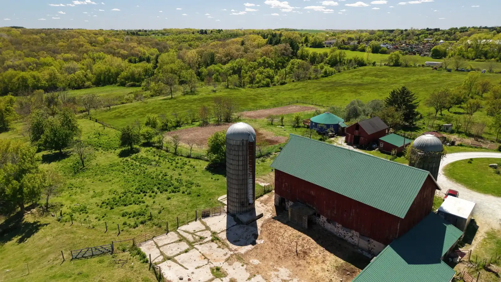 Two silos and the green-roofed red barn at the Goldstein Farm, with Walworth County woods and fields beyond